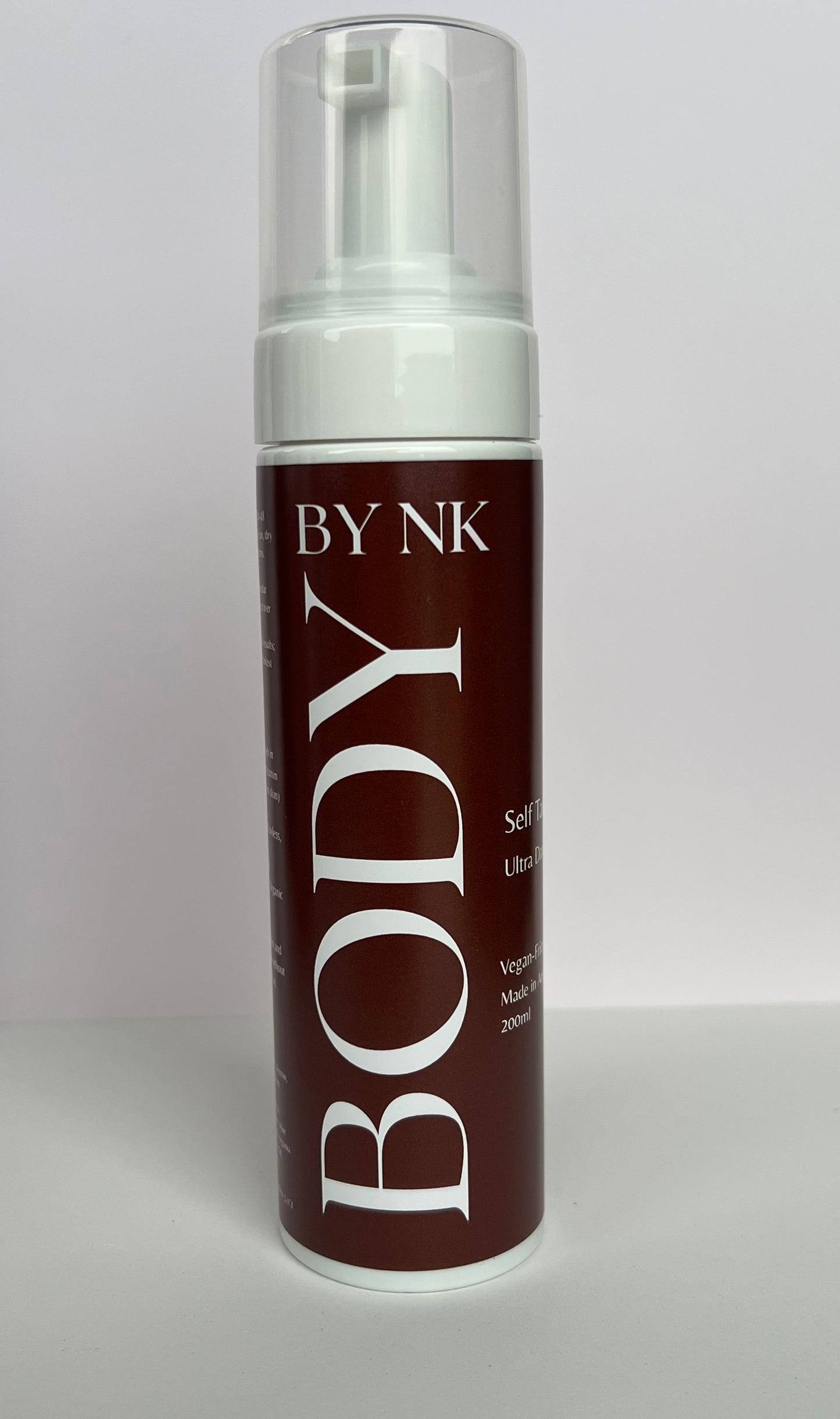 Brown self tanning mousse bottle labeled 'BY NK Body' on a white background