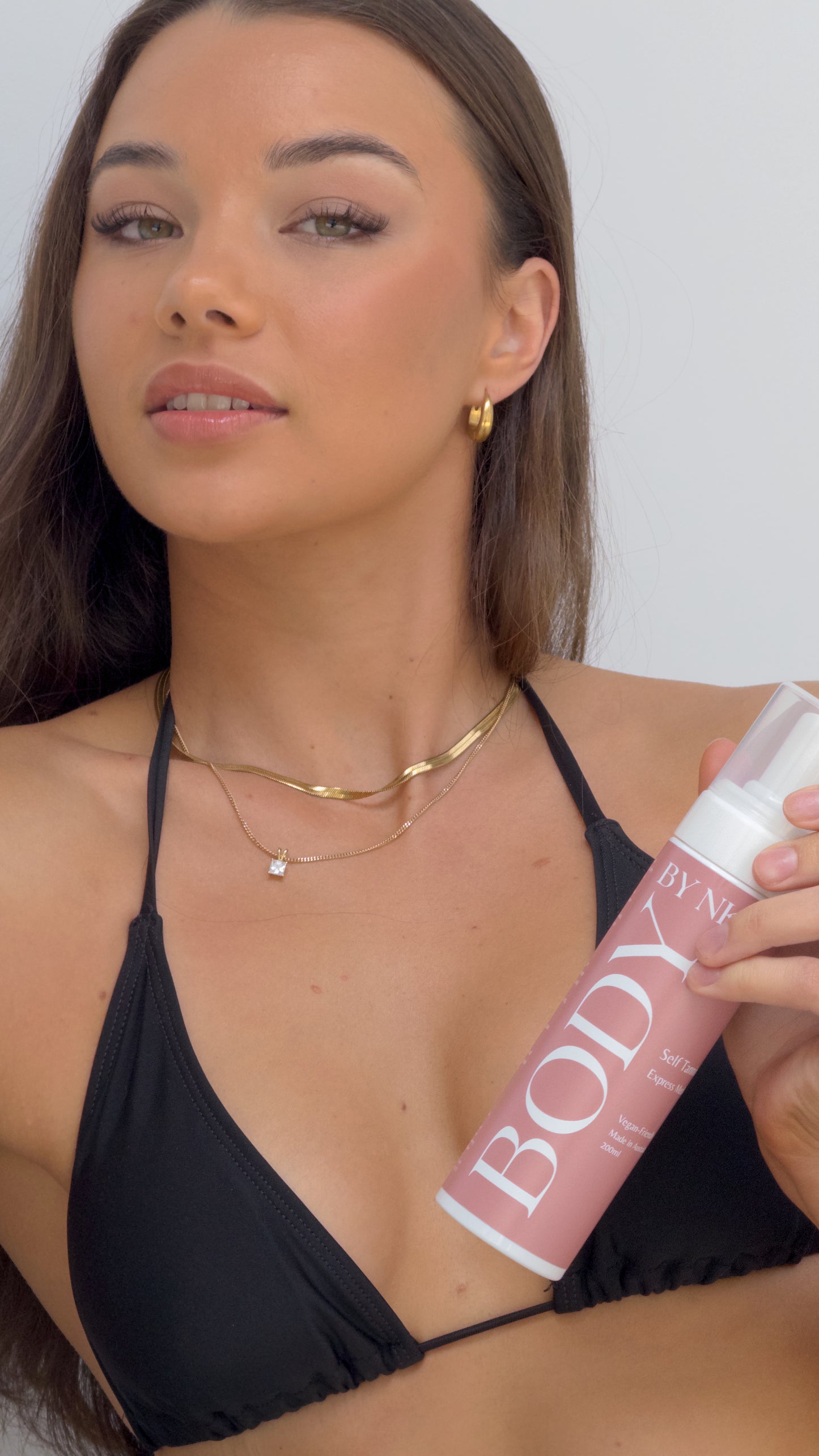 Woman holding a 'BODY' spray can against a plain background