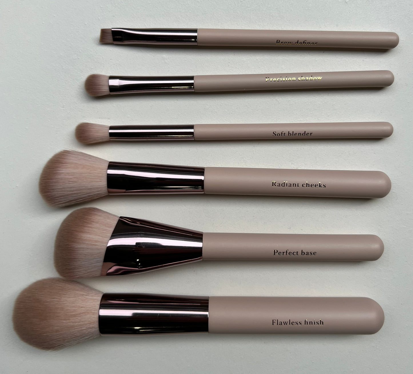 Set of makeup brushes with brown handles and black ferrules on a white surface