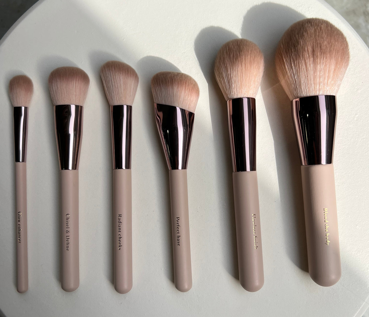 Set of makeup brushes on a round white plate with a neutral background