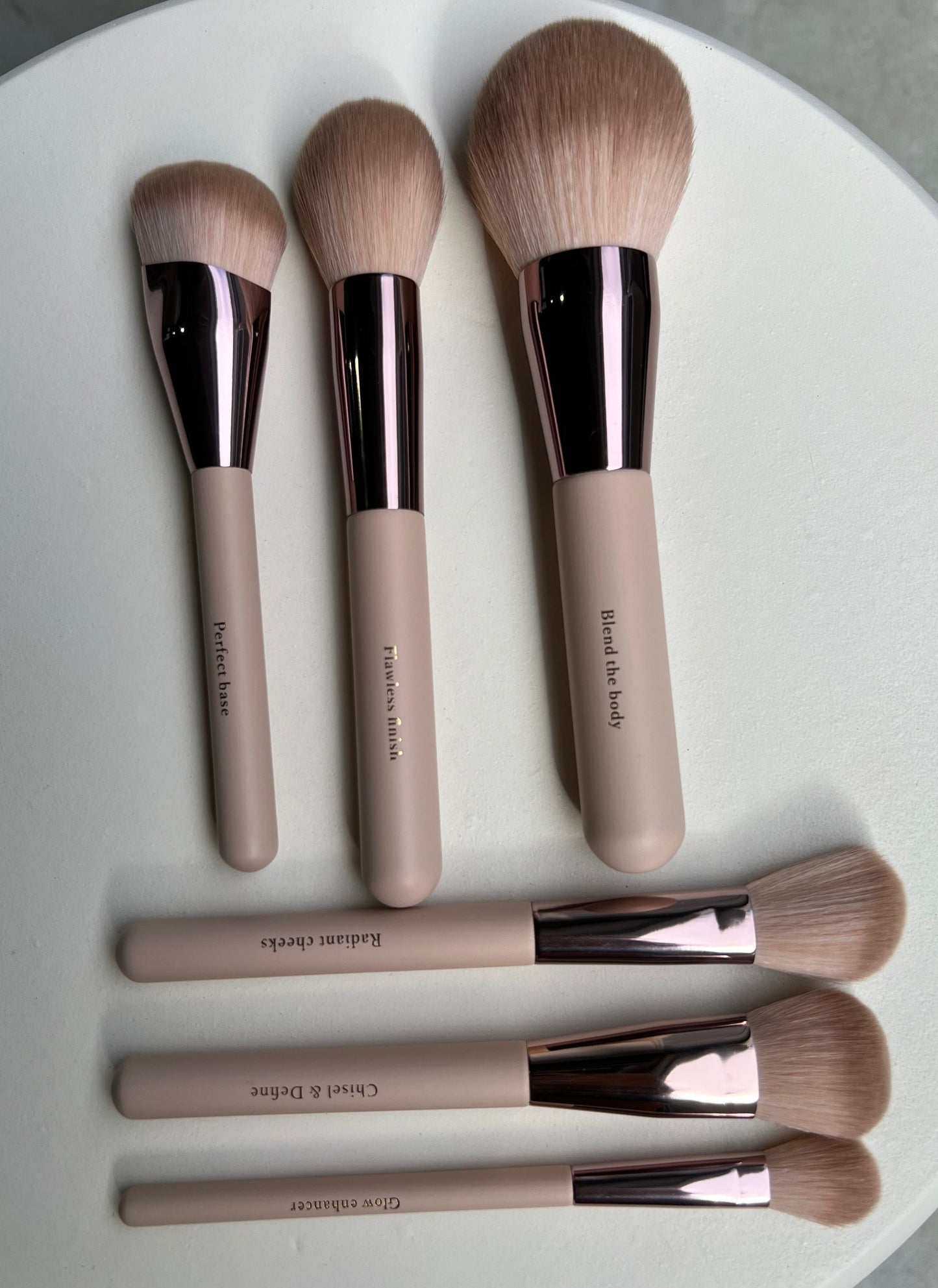 Set of makeup brushes with rose gold accents on a white surface