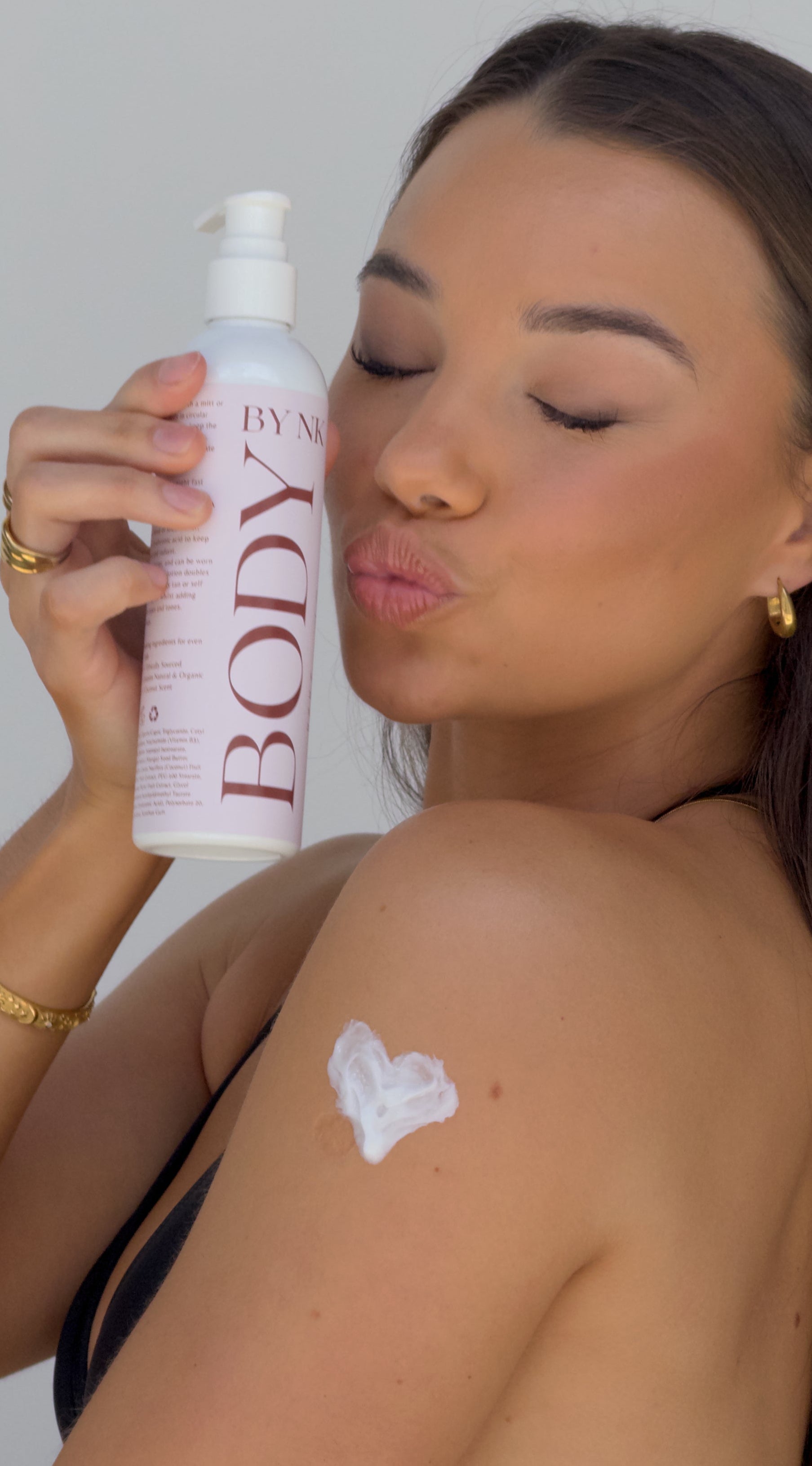 Woman applying sunscreen to her shoulder with a 'BODY' by BANANA BOAT' bottle.