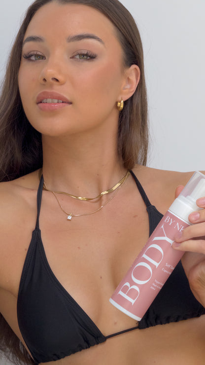 Woman holding a 'BODY' spray can against a plain background