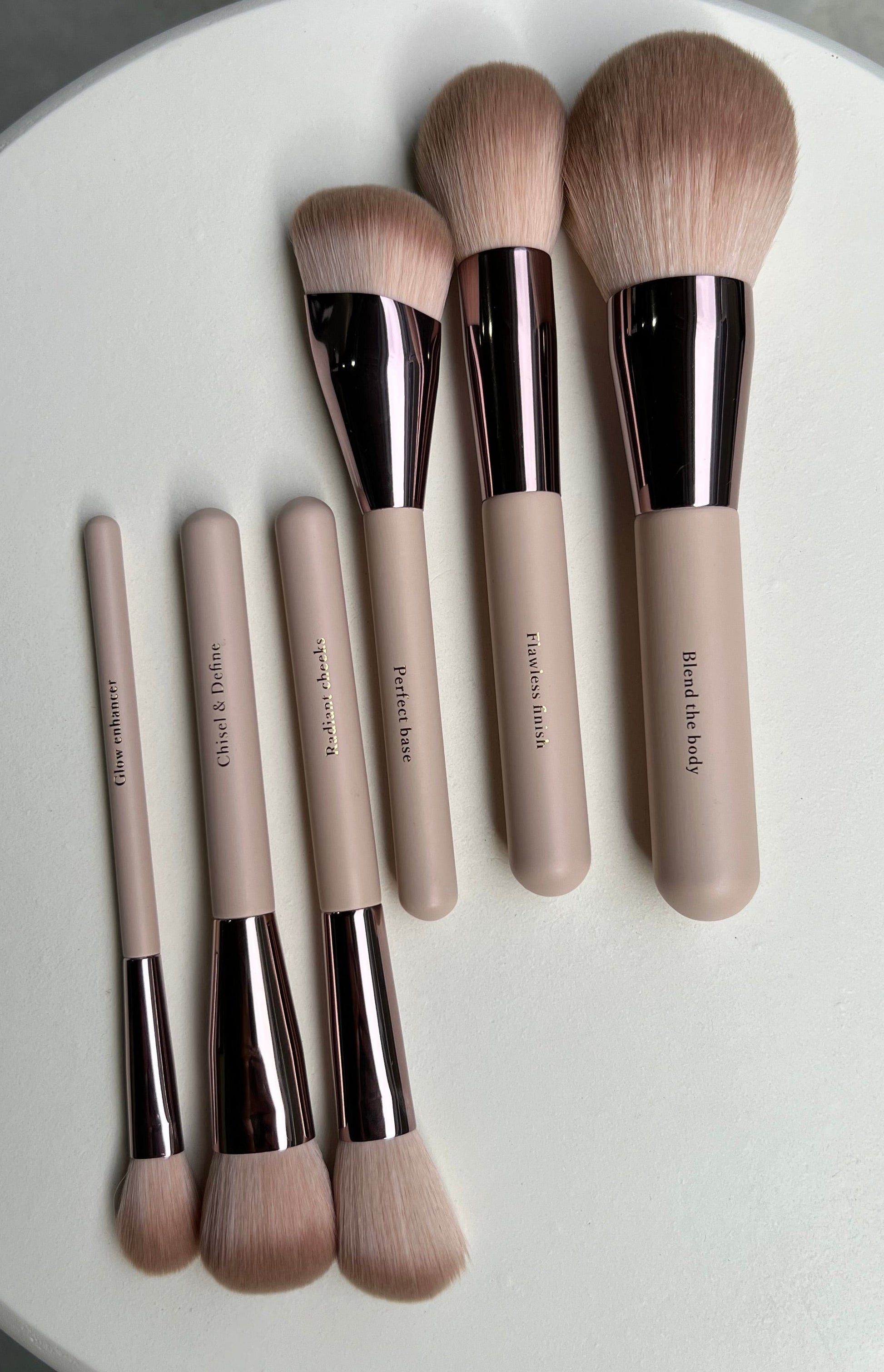 Set of makeup brushes with rose gold and beige handles on a white background