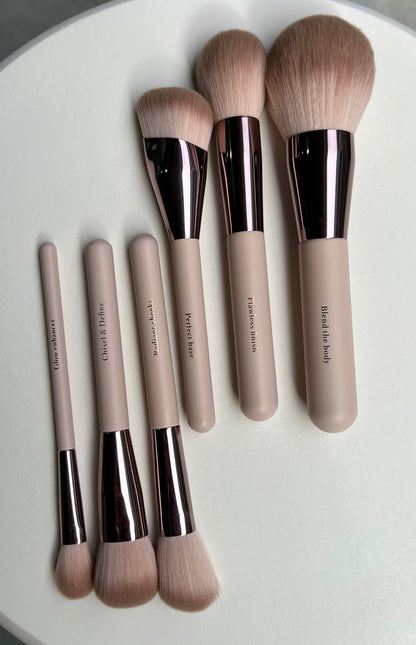 Set of makeup brushes with rose gold and beige handles on a white background