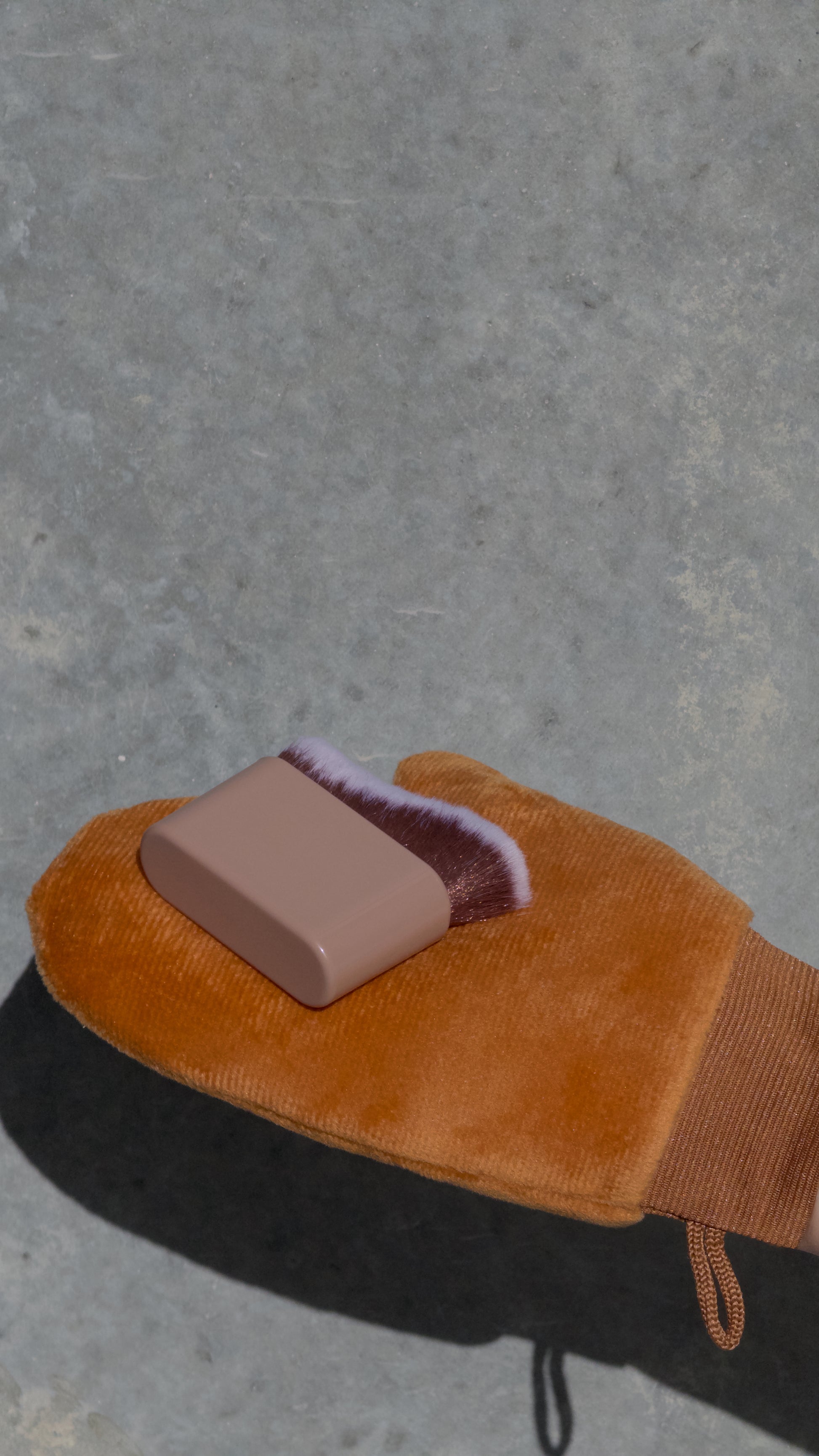 Brown glove with a pink square on a gray surface