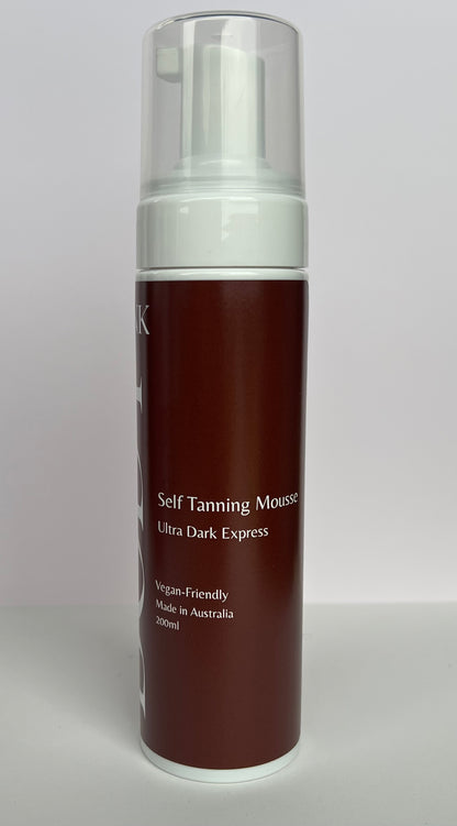 Self tanning mousse bottle with brown body and white cap on a light gray background